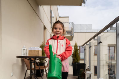 Portrait of young woman standing against building