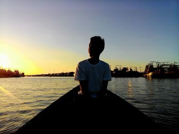 Man standing on sea against clear sky during sunset