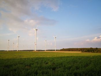 Windmills on field against sky