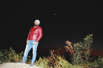 Rear view of man standing on rock at night