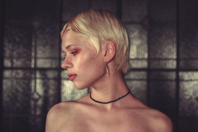 Close-up of young woman looking away against wall