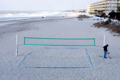 High angle view of man standing by volleyball net at beach