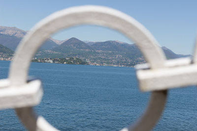 Close-up of metal against sea against clear sky