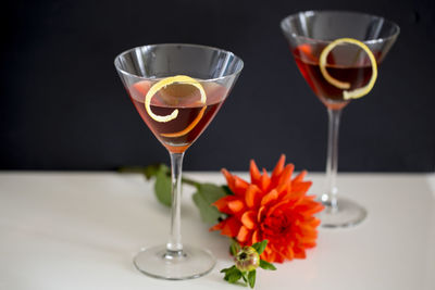 Close-up of alcoholic drinks with flower on table against black background