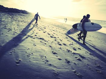 Silhouette people standing on sand against sky