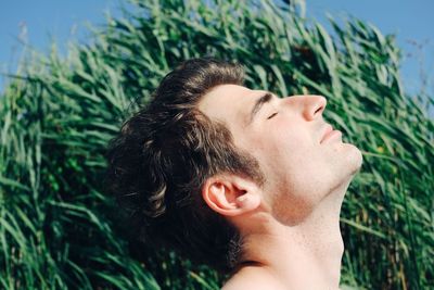 Close-up of man with eyes closed against plants