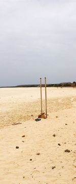 Wooden posts on beach against sky
