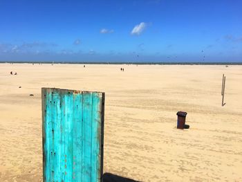 Wooden posts on beach against blue sky