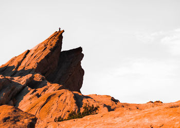 Wide landscape shot of people hiking up a rocky cliff.