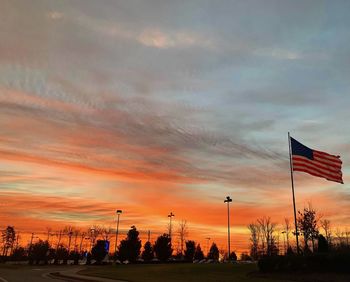 Low angle view of silhouette flag against orange sky