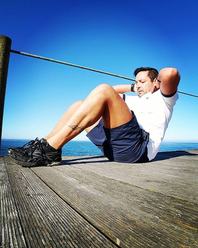 clear sky, sea, casual clothing, lifestyles, young adult, water, person, full length, leisure activity, blue, standing, young men, copy space, beach, sitting, sunlight, vacations