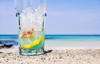 Close-up of drink at beach against sky