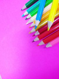 High angle view of colored pencils on pink table