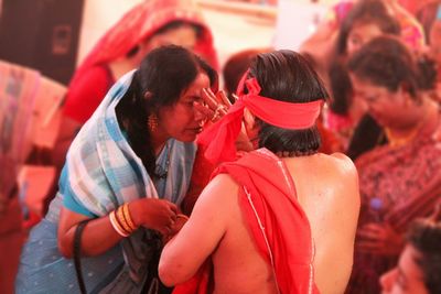 Man applying tilaka to woman by females during event
