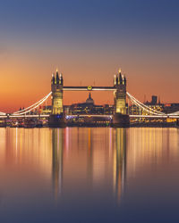 Illuminated bridge over river in city against sky