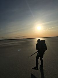 Silhouette man tour skating on field during sunset