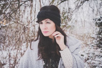 Woman in warm clothing against bare tree during winter