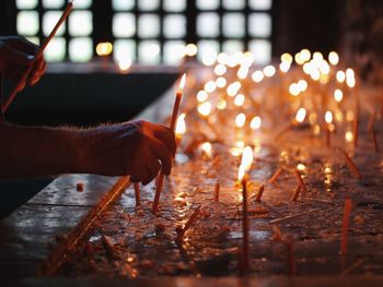 Cropped hand of man offering lit candle at cozia monastery