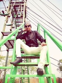 Portrait of young man sitting on railing