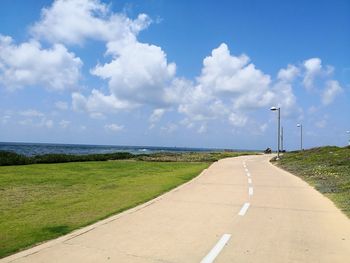 Empty road by sea against sky