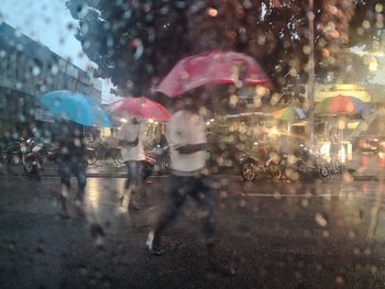 People seen through wet window in rainy season