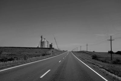 Road by electricity pylon against sky