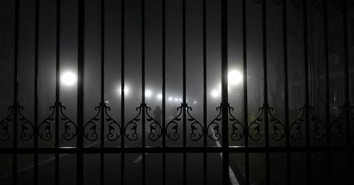 Illuminated lights on railing against sky at night