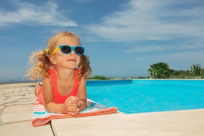 Portrait of young woman wearing sunglasses against swimming pool