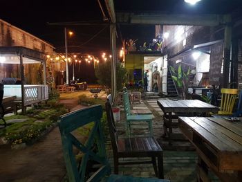 Empty chairs and tables in street at night