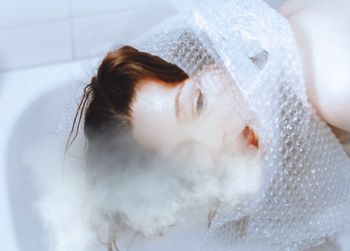 Woman with bubble wrap bathing in bathroom