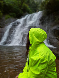 Rear view of woman standing against waterfall