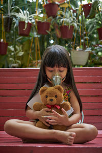 Full length of woman holding toy while sitting outdoors