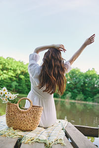 Rear view of woman with arms outstretched standing in basket