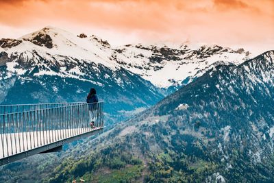 Woman looking at snowcapped mountains against sky