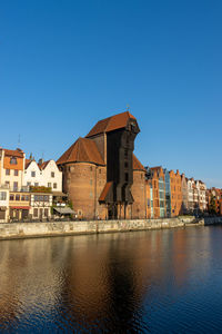 Buildings at waterfront against blue sky