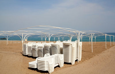 Deck chairs on beach against clear sky