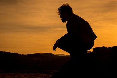 Silhouette man standing against orange sky