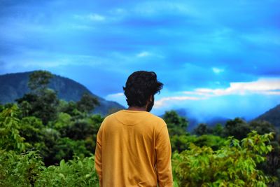 Rear view of man looking at mountain against sky