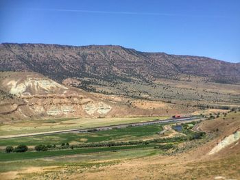 Scenic view of field and mountains against clear sky