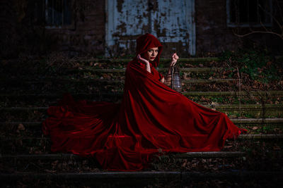 Woman with red umbrella standing on land