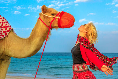 Woman with camel standing at beach