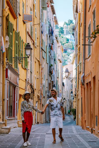 Rear view of people walking on alley amidst buildings in city