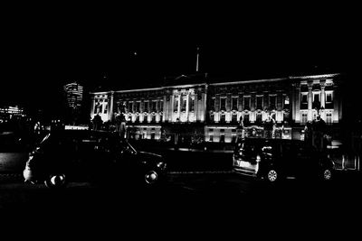 Cars on illuminated city street against sky at night