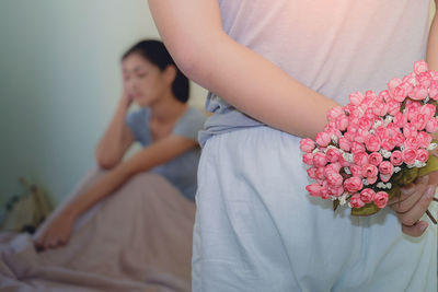 Close-up of couple holding pink flower on bed