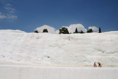 People on snow covered mountain against blue sky