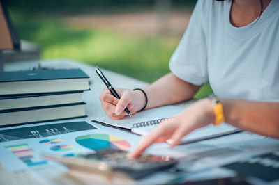 Midsection of woman holding paper with text on table