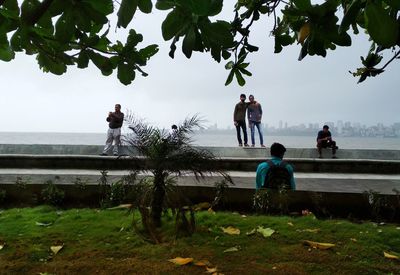 People standing by river against sky