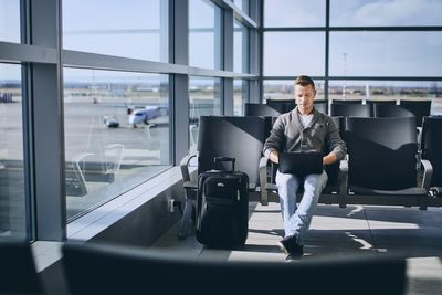 Full length portrait of woman sitting in airport