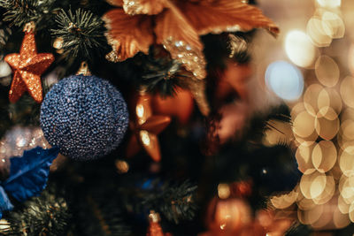 Golden star and blue christmas ball hanging on a christmas tree with garland lights.