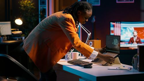 Side view of woman using laptop at office